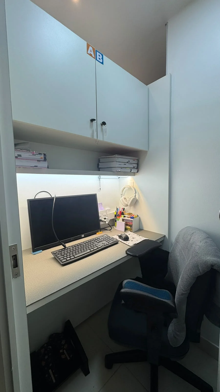 Cabine fechada com monitor, teclado e armário
